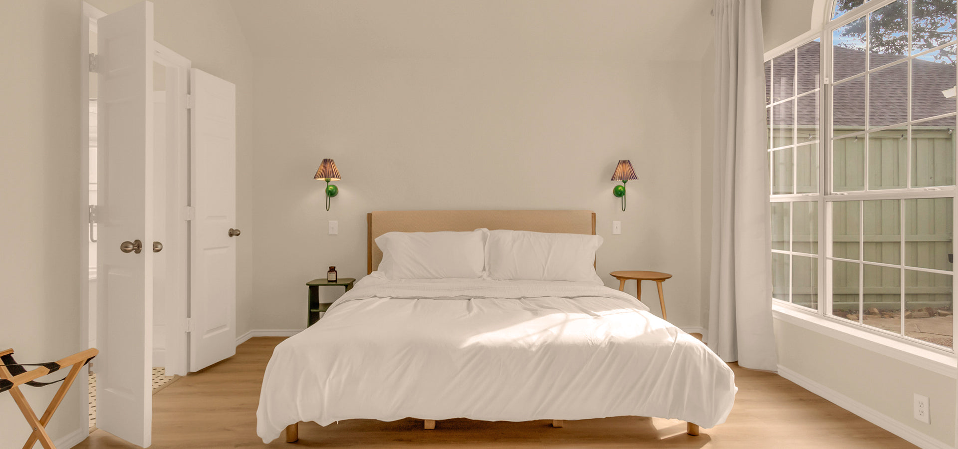 Master bedroom with a king bed, large windows, and bright natural light at Alfresco Cottage.
